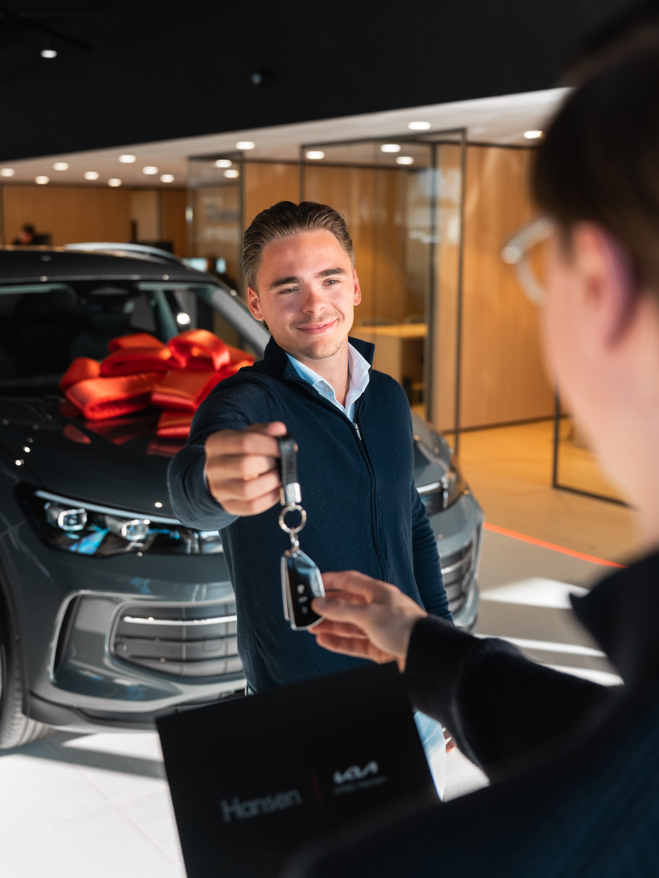 Een verkoper van Hansen overhandigt de autosleutel aan een klant